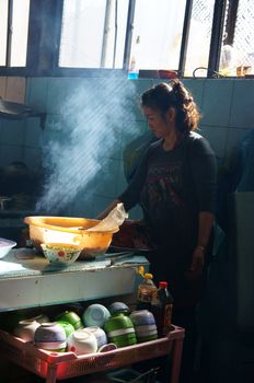 DA LAT, VIET NAM- DEC 28: Chef working at rice restaurant, she broit meat for com tam meal, this is specific of vietnamese food in Dalat, Vietnam on Dec 28, 2013