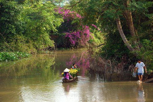 SA DEC, VIET NAM, ASIA- JAN 26: Spring come, women and children rowing the rowboat on river to carry beautiful flower  forTet (lunar new year) in springtime Sa Dec, Vietnam, Asia Jan 26, 2013 