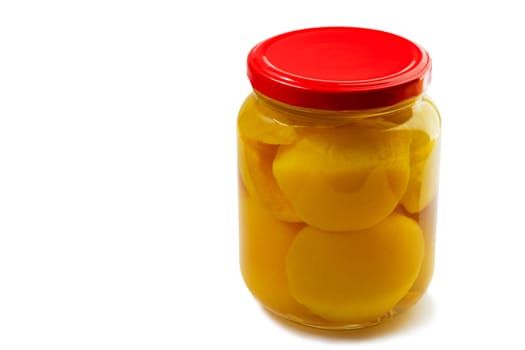 Slices of canned peaches in syrup in a glass jar.
Presented on a white background.