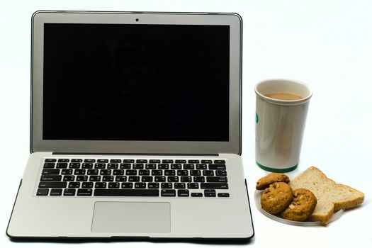 Office desk with laptop,cookie bread and cup of coffee