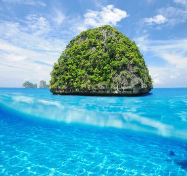 Beautiful uninhabited island in Thailand with white sand bottom underwater and above water split view