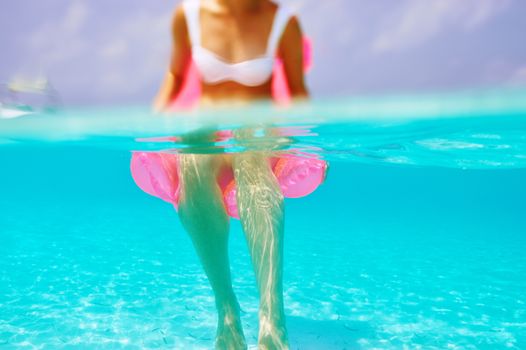 Woman relaxing on inflatable mattress at the beach, view from underwater