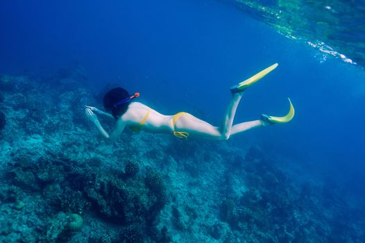 Woman with mask snorkeling in clear water 