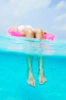 Woman relaxing on inflatable mattress at the beach, view from underwater