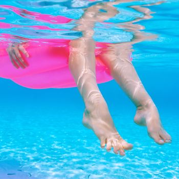 Woman relaxing on inflatable mattress at the beach, view from underwater