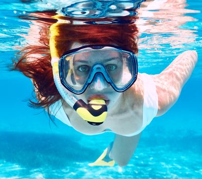 Woman with mask snorkeling in clear water 