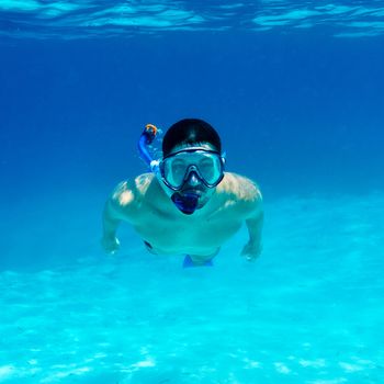 Man with mask snorkeling in clear water 