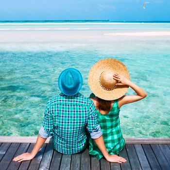 Couple on a tropical beach jetty at Maldives