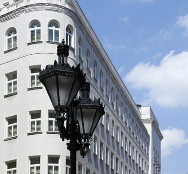 Ornate metal street lamp white building in the background.