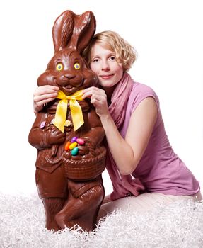 Blond Girl Adjusting Bowtie of a Chocolate Easter Bunny Isolated on White Background
