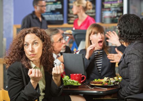 Angry woman with clenched fists at table with coworkers