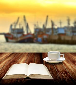 Read book with coffee cup beside jetty