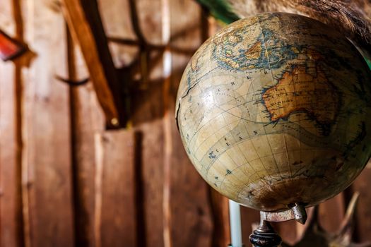 Old, damaged, old-style globe against brown  wooden wall, copy space.