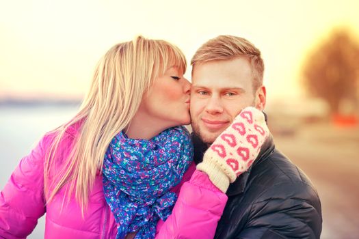 Young woman is giving a kiss to her boyfriend in a warm filtered tones