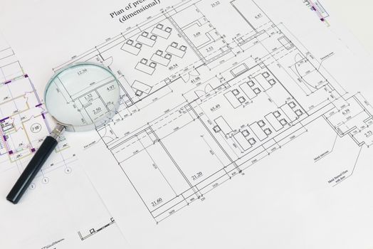 Construction drawing and magnifying glass . The desk architect