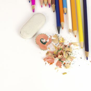 Color pencils, shavings and eraser on a white paper background
