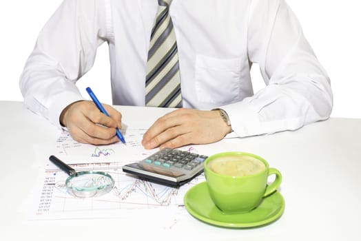 Businessman sitting at a table and writes. Financial papers in front of him