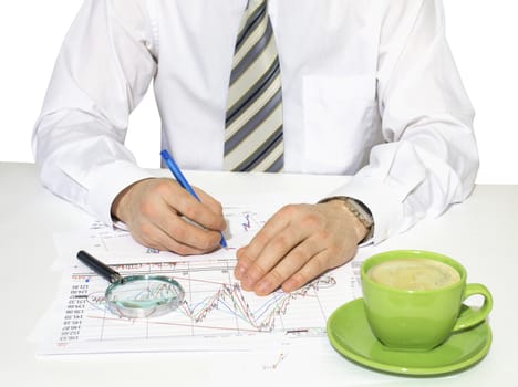 Businessman sitting at a table and writes. Financial papers in front of him