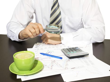 Businessman sitting at table and holding a magnifying glass. Financial papers in front of him