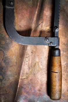 Manual saw on metal on a leaf of copper