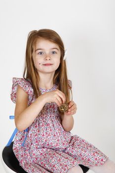 Young smiling girl sitting on a chair. smelling perfume