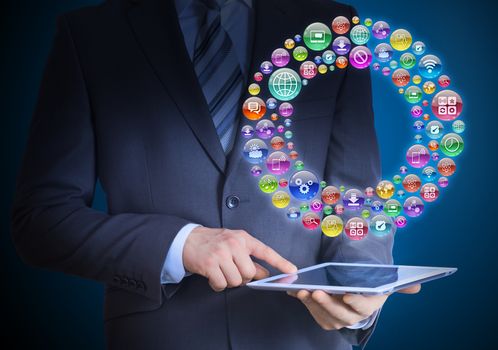 Businessman in a suit holding a tablet in his hands. Above the screen tablet application icons in the form of disk