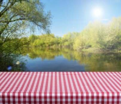 Empty checkered table with spring lake in background. Ready for product display montage. 