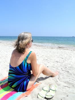 Mature female blond beauty relaxing on the beach.