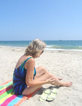 Mature female blond beauty relaxing on the beach.