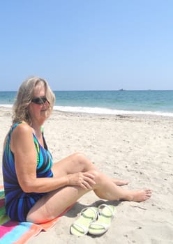 Mature female blond beauty relaxing on the beach.