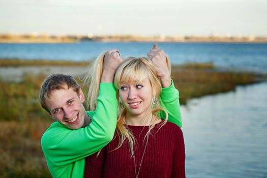 Young couple fooling around on the beach day in autumn