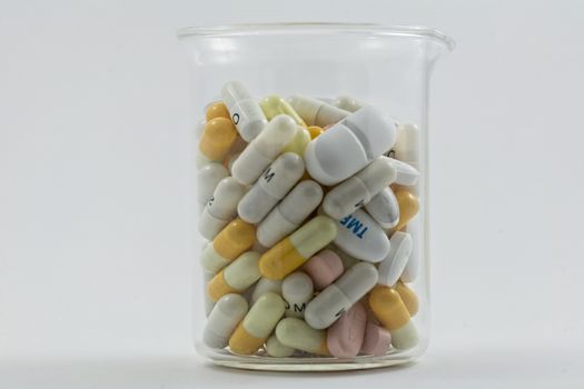 Flask full of pills of different sizes isolated on a white background