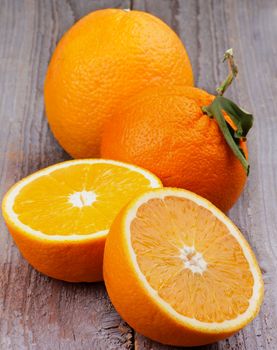 Arrangement of Full Body and Halves of Juicy Ripe Orange closeup on Rustic Wooden background