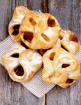 Arrangement of Homemade Pastry Baskets Jam Wrapped with Sugar Powder on Wicker Napkin closeup on Rustic Wooden background. Top View