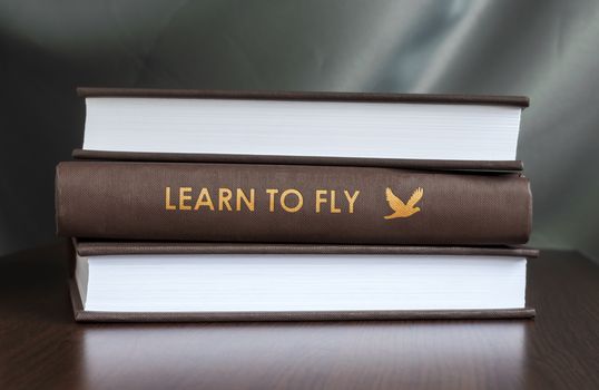 Books on a table and one with " Learn to fly. " cover. Book concept.