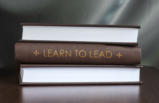Books on a table and one with "Learn to lead" cover. Book concept.