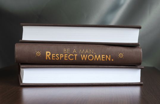 Books on a table and one with " Be a man. Respect women. " cover. Book concept.