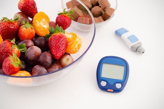 Glucose meter device with accessories. Fruits and chocolates. Healthy lifestyle