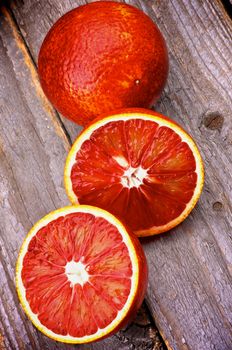 Arrangement of Blood Oranges Full Body and Two Halves isolated on Rustic Wooden background