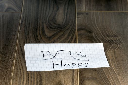 Be happy - Kid writing with a smile face on wood background