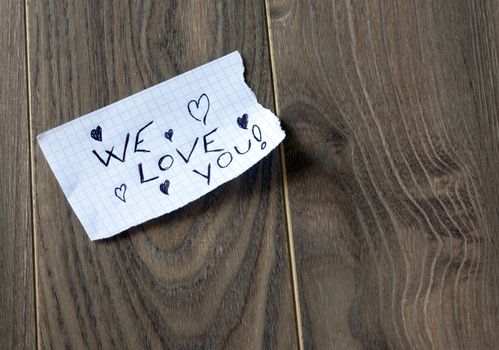 We Love You - Kid writing with a hearts on wood background