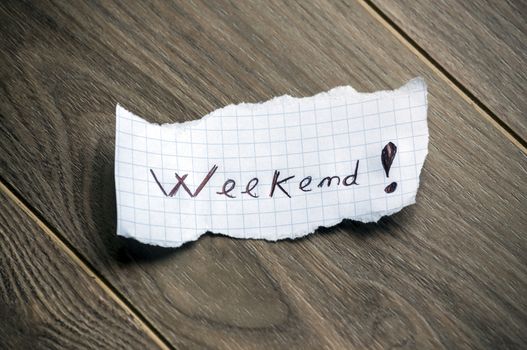 Weekend - Hand writing text on a piece of paper on wood background