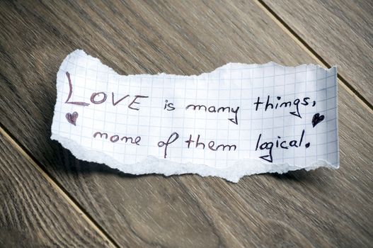 Love is many things, none of them logical (Quote by William Goldman) - Hand writing text on a piece of paper on wood background