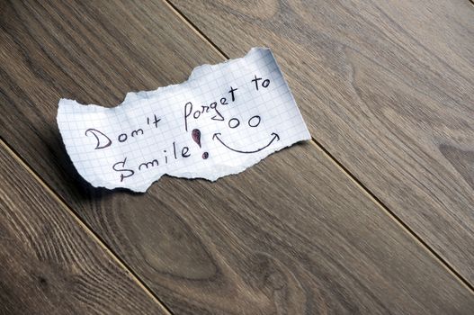 Don't forget to Smile - Hand writing text on a piece of paper on wood background with space for text