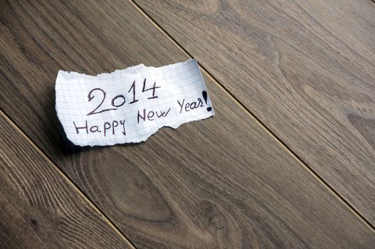 Happy new Year 2014 - Hand writing text on a piece of paper on wood background with space for text