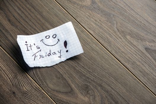 It's Friday - Hand writing text on a piece of paper on wood background with space for text