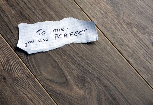 To me, you are Perfect - Hand writing text on a piece of paper on wood background with space for text