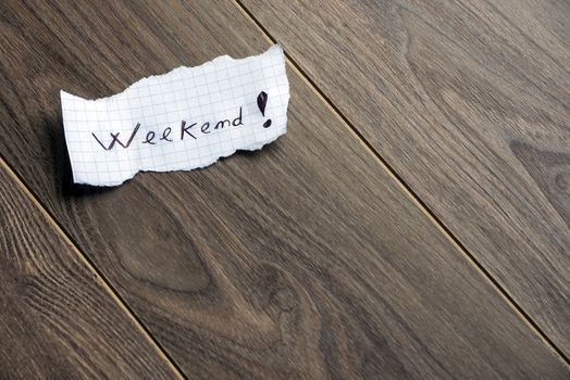 Weekend - Hand writing text on a piece of paper on wood background with space for text