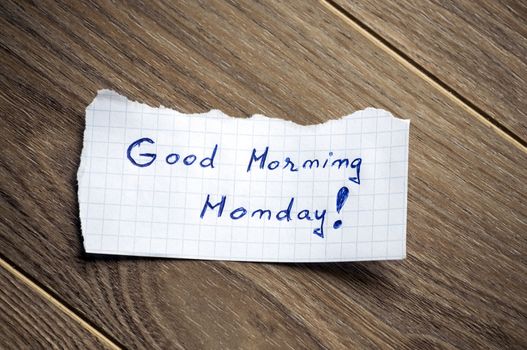 Good Morning Monday written on piece of paper, on a wood background.