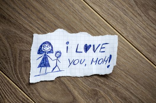 I love you, mom written on piece of paper, on a wood background